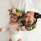 Overhead view of mother and baby girl wearing flower crowns lying on a white rug.