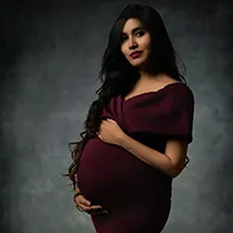 Fine art maternity photos from a maternity photoshoot of a woman in a burgundy dress for her photo shoot for pregnant woman.