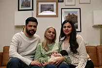 Three generations of a family sitting on a sofa with the newborn baby girl for a family photoshoot.