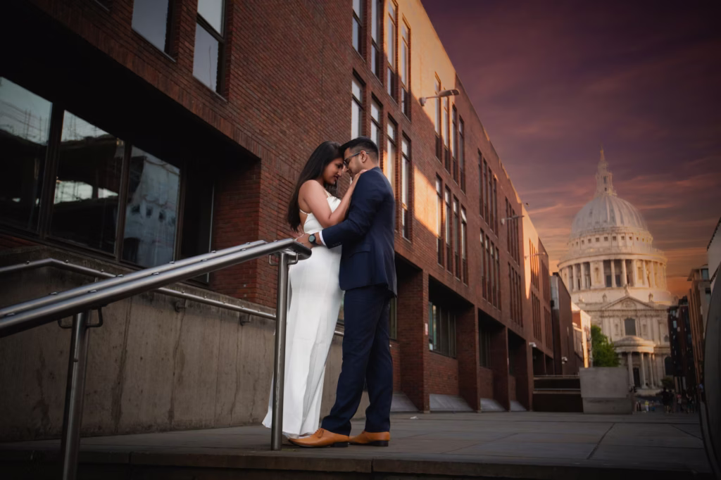 Romantic profile shot of couple standing close together against modern brick building backdrop touching foreheads in private moment with St. Paul's Cathedral visible in distance - pre wedding photoshoot london