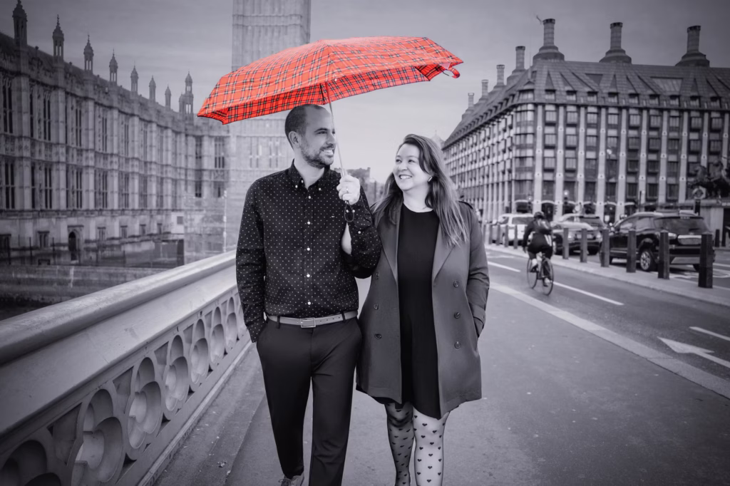 A couple under a red umbrella by Westminster, in black and white