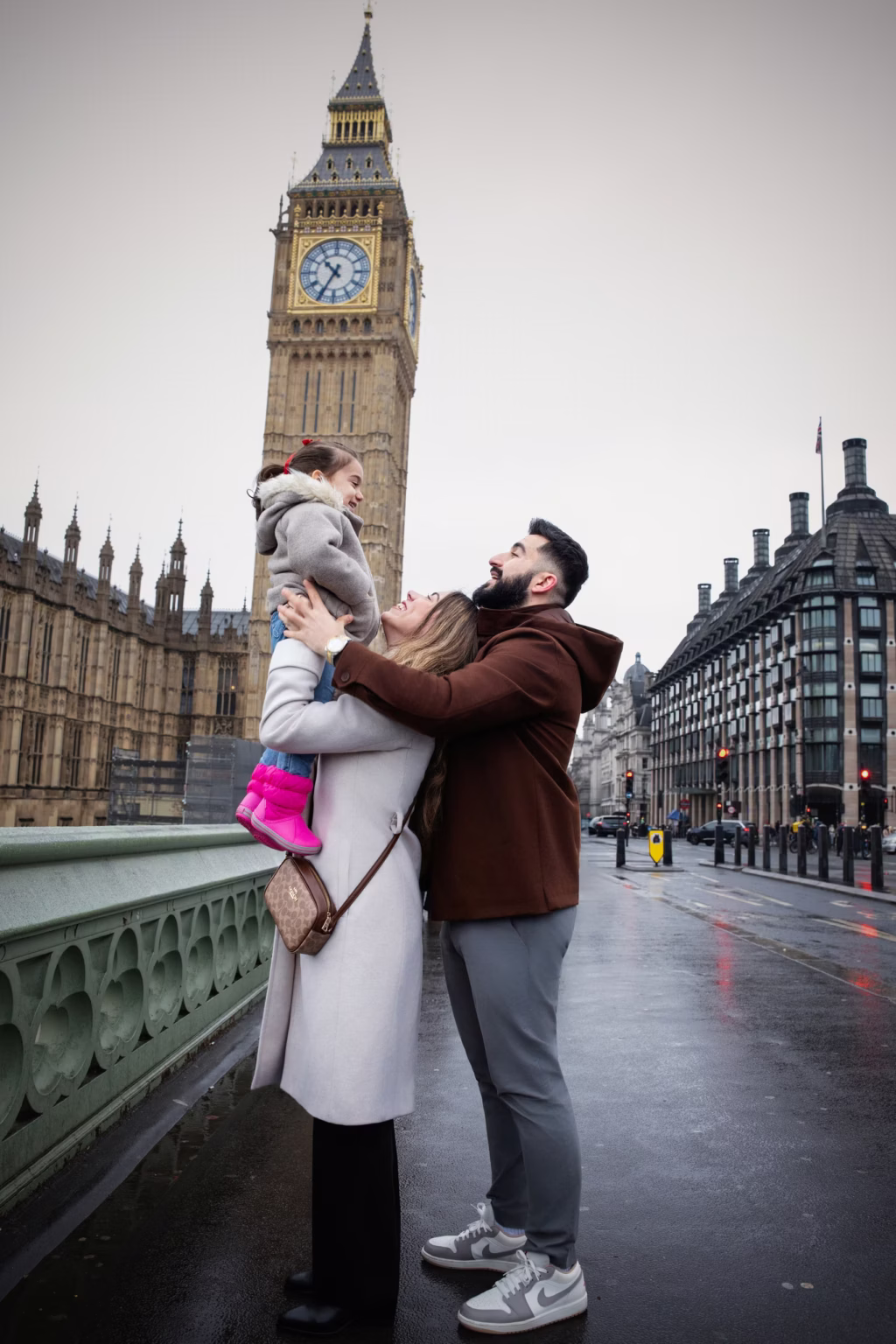 London family portraits of parents lifting daughter on Westminster Bridge with Big Ben