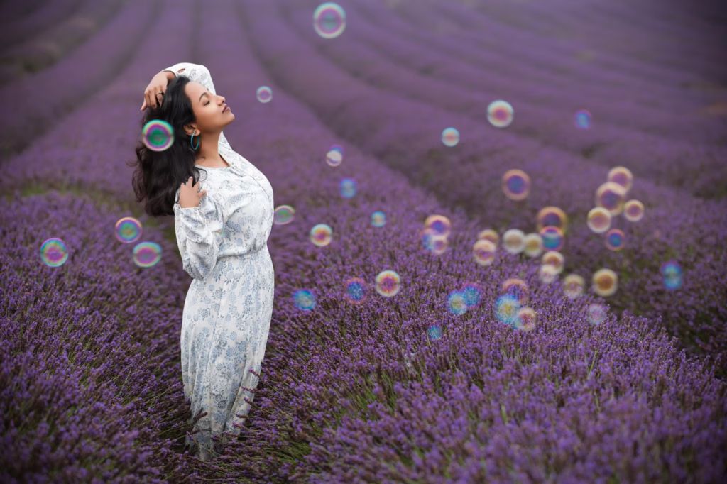 London Fashion Photography London serene lifestyle shot of woman in white long-sleeved dress in lavender field with floating iridescent bubbles and peaceful closed-eye pose