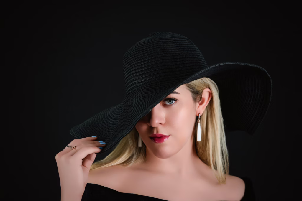 London Fashion Photography Photographers - Variation hat shot blonde model slightly more front-on angle holding brim large black hat revealing more face white rectangular statement earrings
