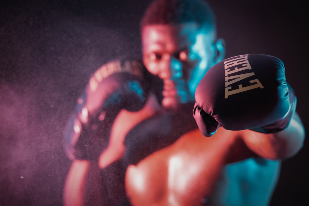 London Fashion Studio Photoshoot - Dynamic low-key action shot boxer black Everlast boxing glove extended toward camera sharp focus soft focus model face atmospheric cyan magenta lighting dust mist haze