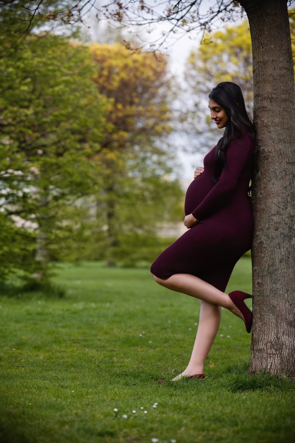 Expectant mother leaning against a tree in a London park