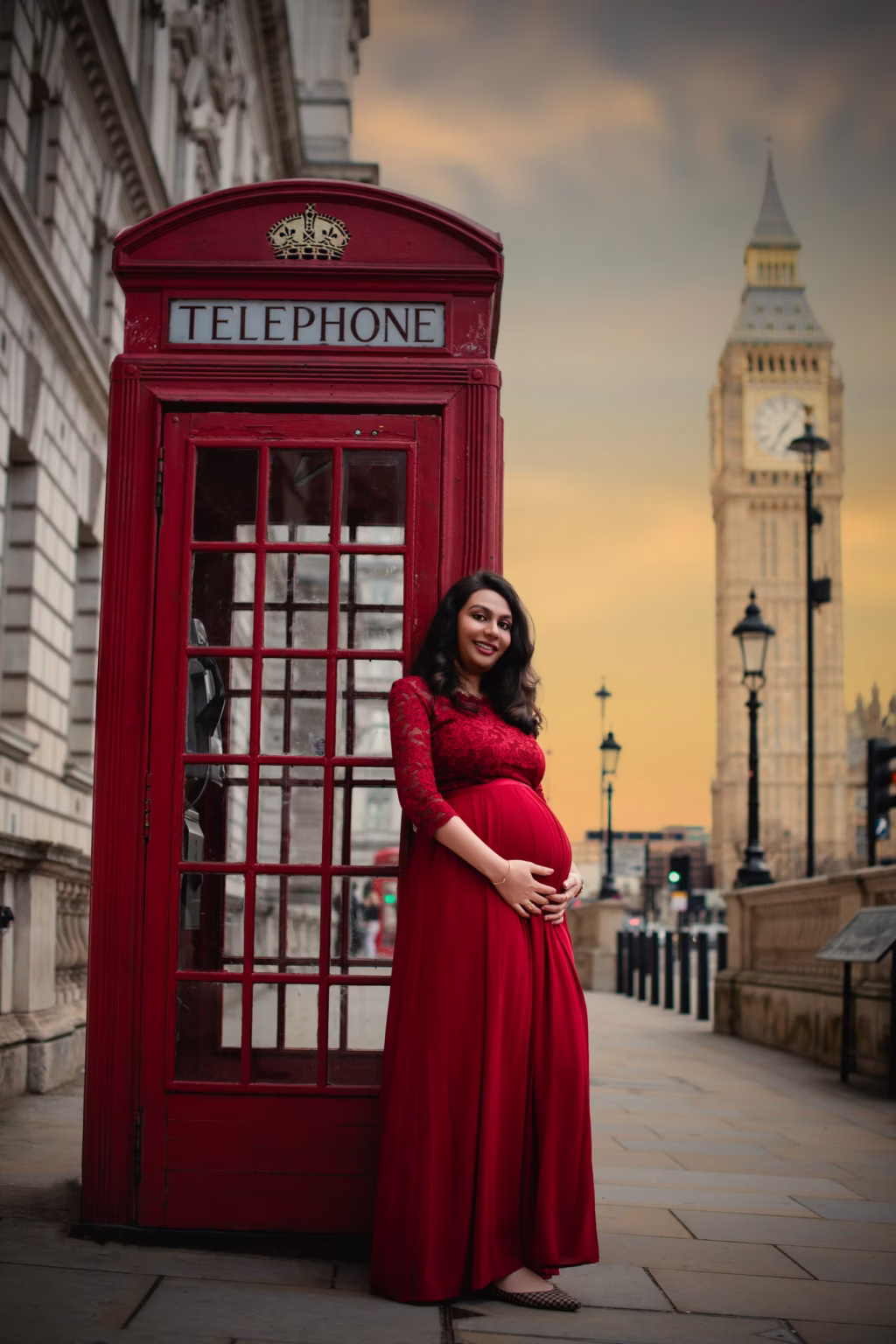 Expectant mother beside a red telephone box near Big Ben