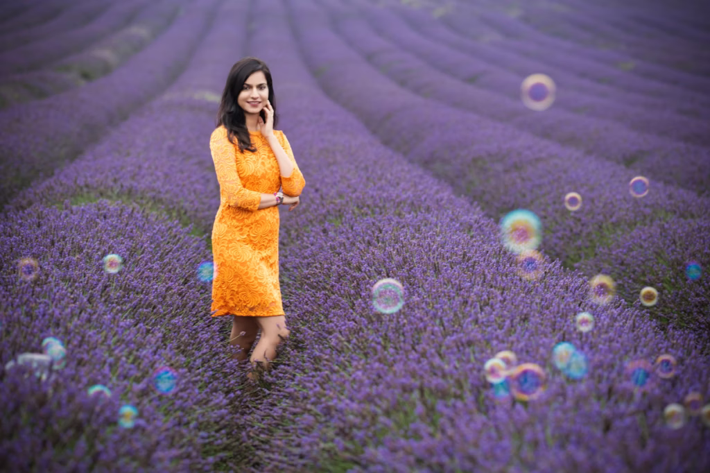 Model photoshoot london - fashion photographer, Picturesque lifestyle shot woman bright orange lace dress standing lavender field floating iridescent bubbles rows purple lavender blurred rhythmic background